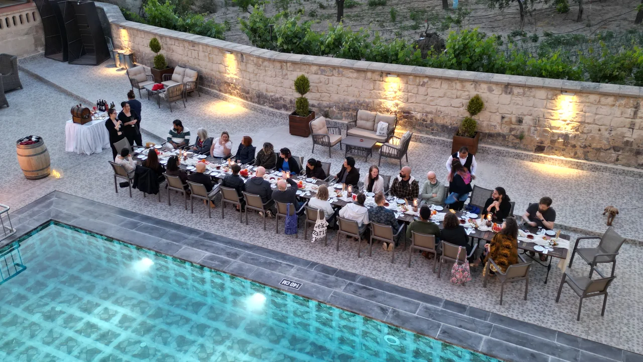 Ospiti a cena a una lunga tavola accanto alla piscina