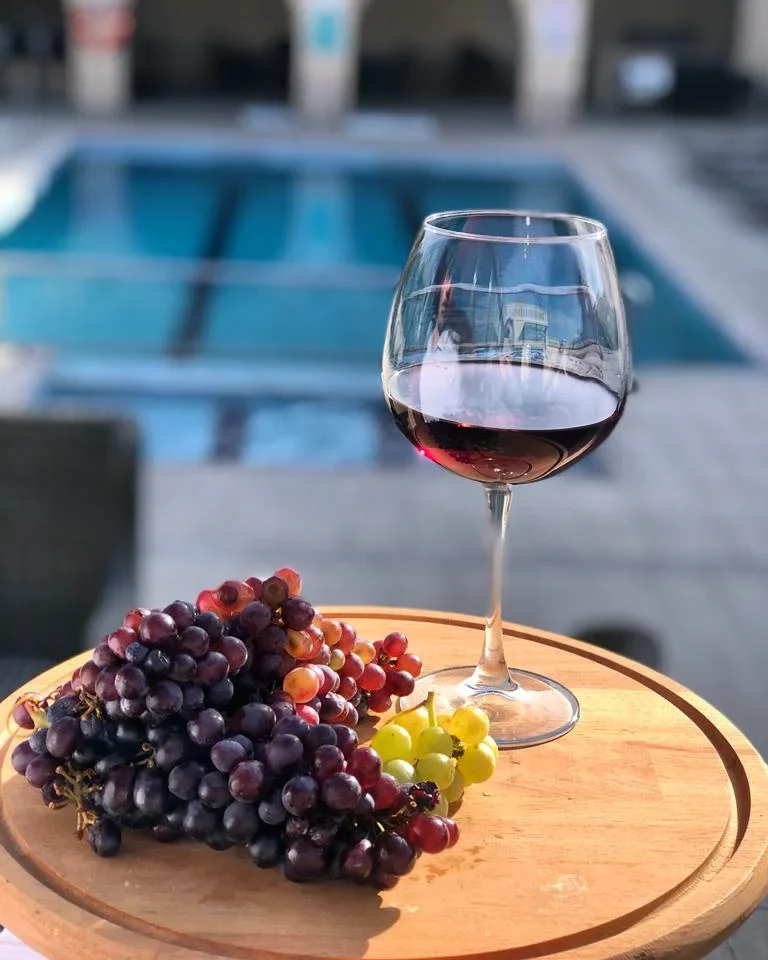 Un calice di vino rosso e uva accanto alla piscina