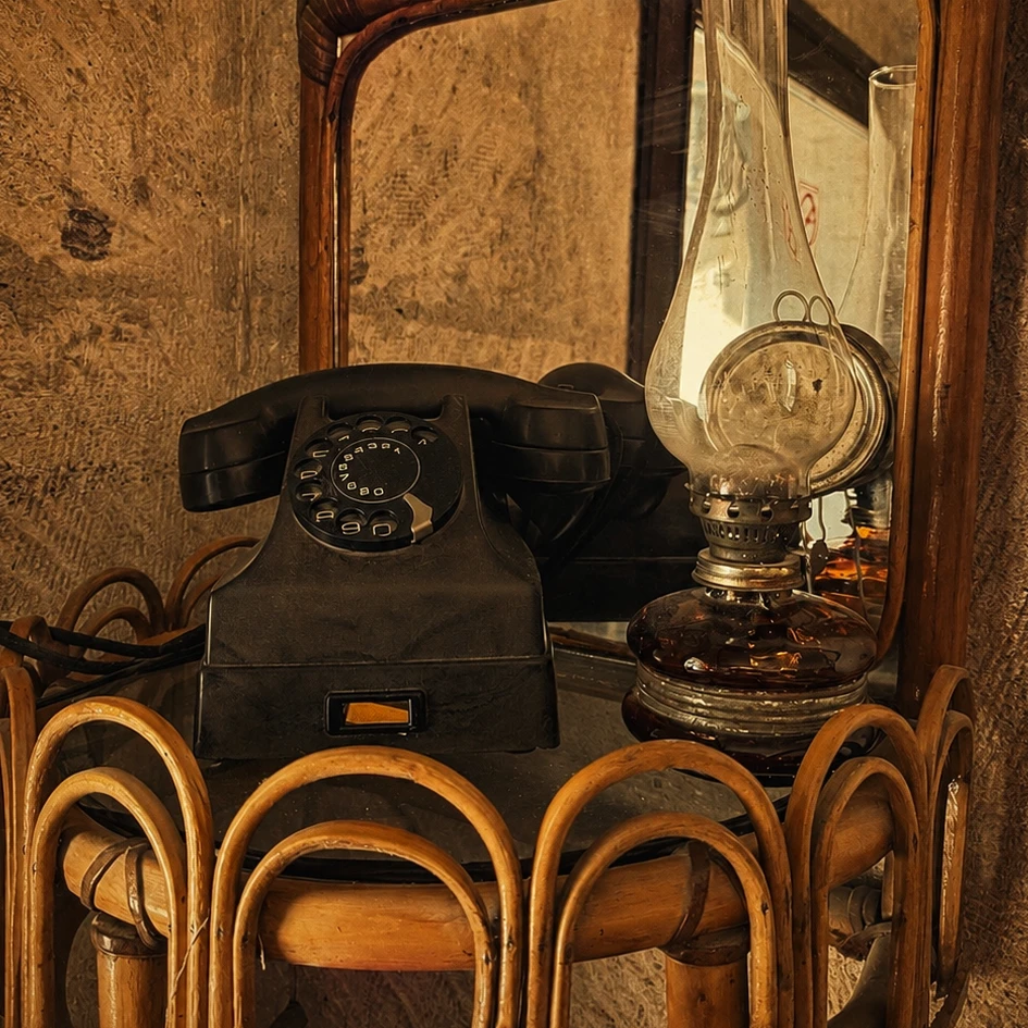 A vintage rotary phone and oil lamp against a stone wall at Dilek Kaya Hotel