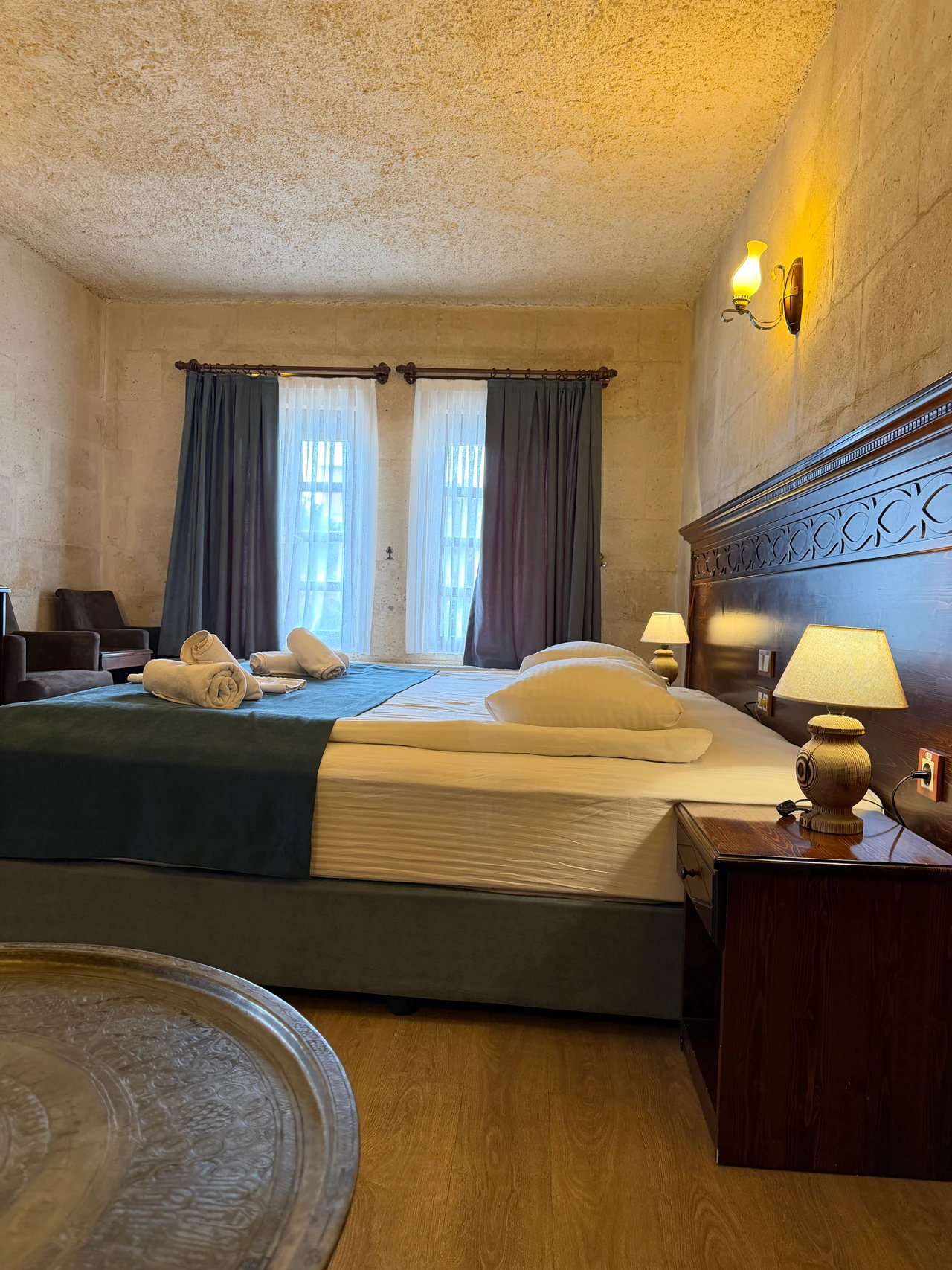 Doppelbett mit Holzkopfteil und Sessel an den Fenstern in der King Suite